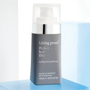 A bottle of Perfect hair Day™ Healthy Hair Perfector sits on a white and blue surface, featuring a gray label with the product size of 118 mL (4.0 FL OZ US). This hair treatment is designed for healthier-looking hair.