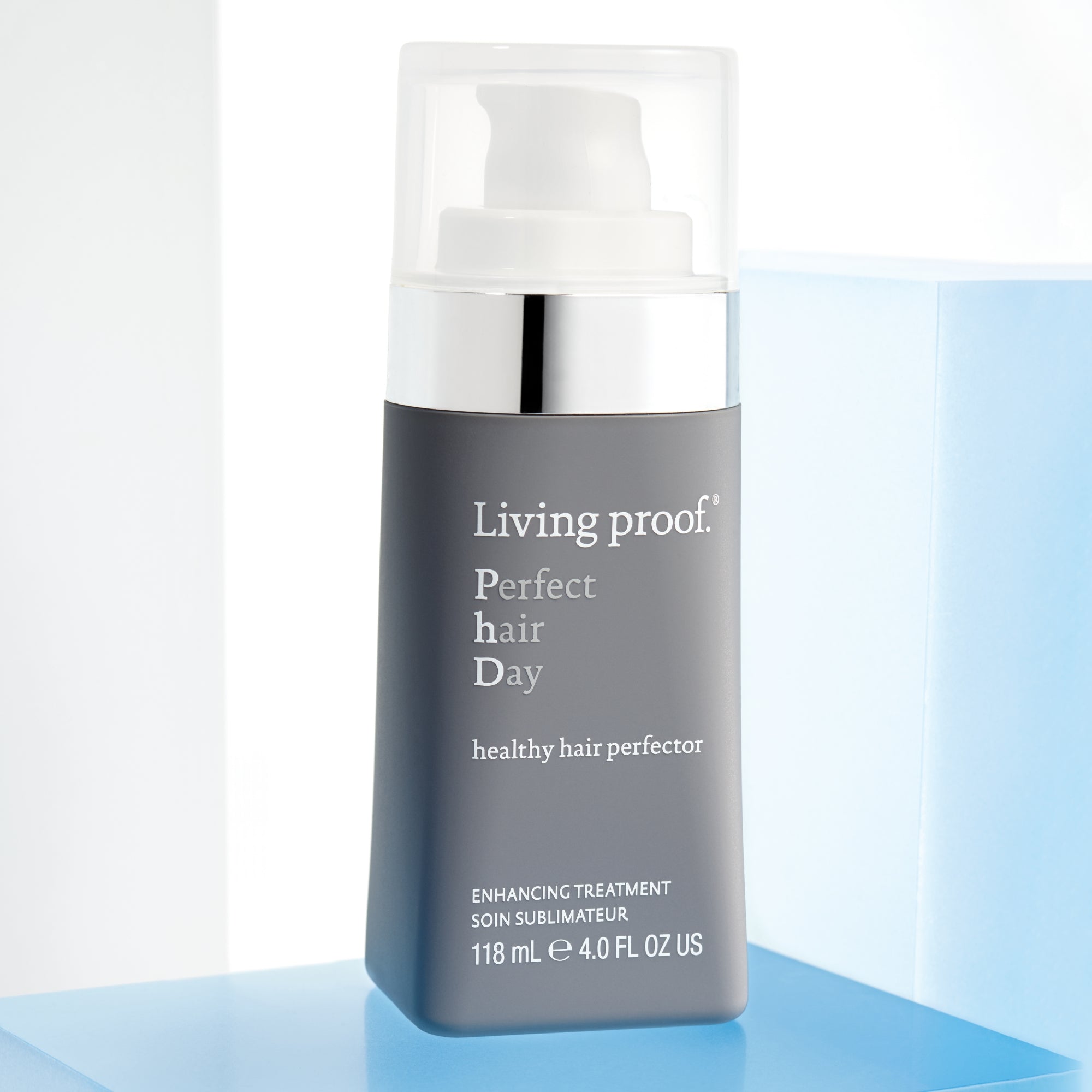 A bottle of Perfect hair Day™ Healthy Hair Perfector sits on a white and blue surface, featuring a gray label with the product size of 118 mL (4.0 FL OZ US). This hair treatment is designed for healthier-looking hair.