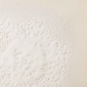 The No Frizz Smooth Styling Spray features a white and cream-colored textured surface with clusters of small dots and a cloudy pattern, similar to detangling powder or mold on a light background.