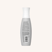 A gray bottle with a white cap, shown from the back with small text and a barcode, sits against an off-white background—a sleek package for Full Volume & Root-Lifting Spray that delivers all-day fullness.