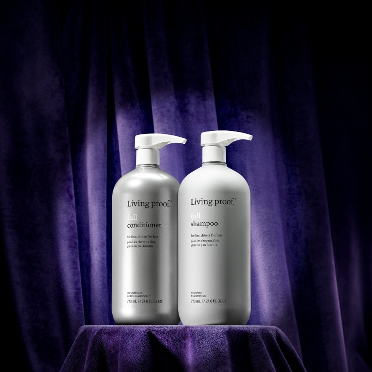 Living Proof shampoo and conditioner bottles on a purple fabric background