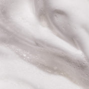 Close-up of Full Thickening Mousse reveals dense, creamy white foam with a cloud-like texture. The voluminous bubbles highlight the mousse’s ability to create impressive body and smooth fullness, enhanced by gentle highlights and shadows.