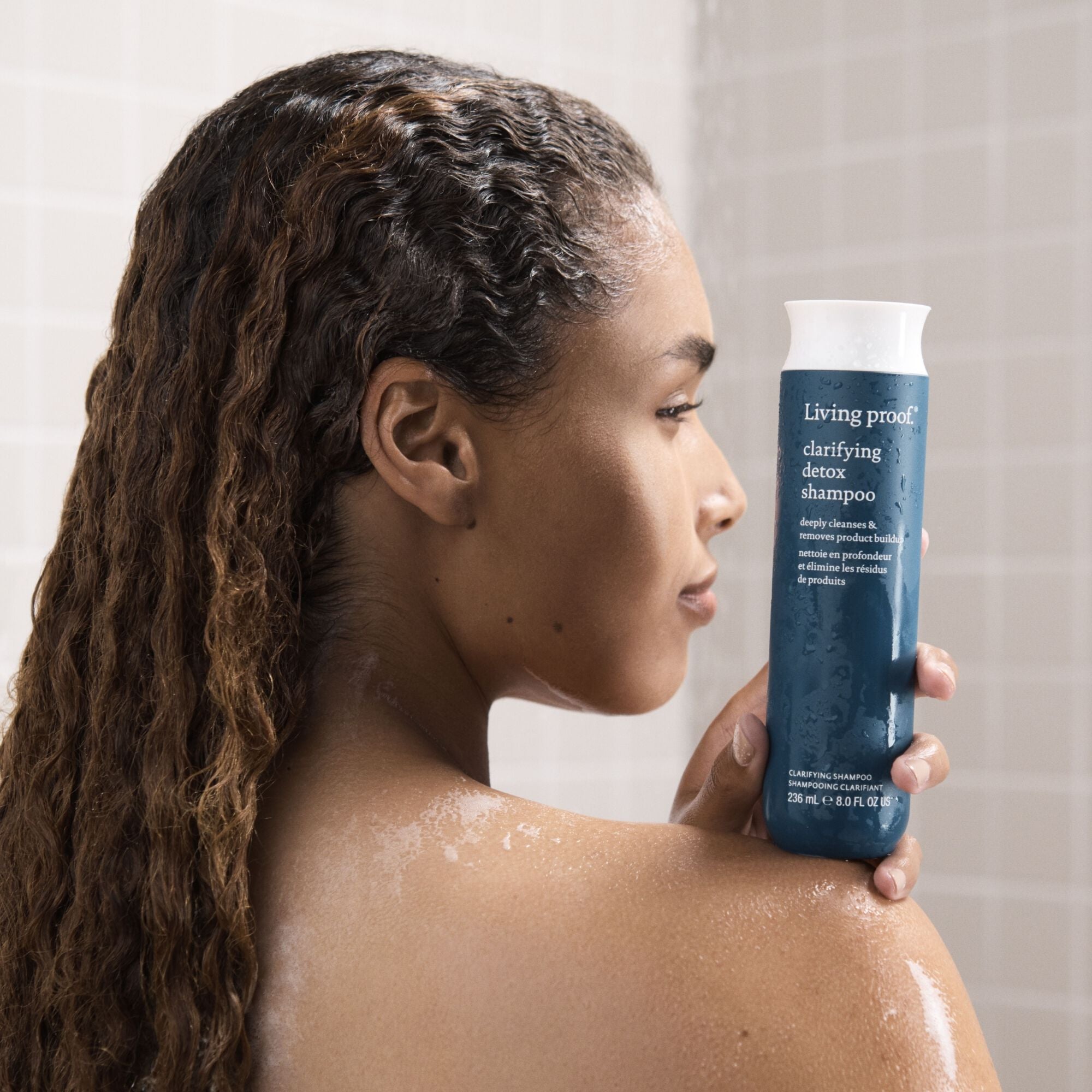 woman holding clarifying detox shampoo in the shower
