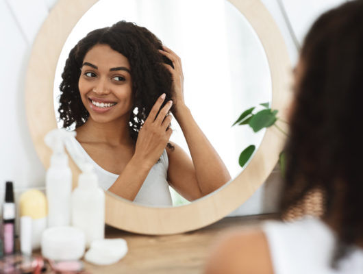 woman touching her hair while looking in a mirror