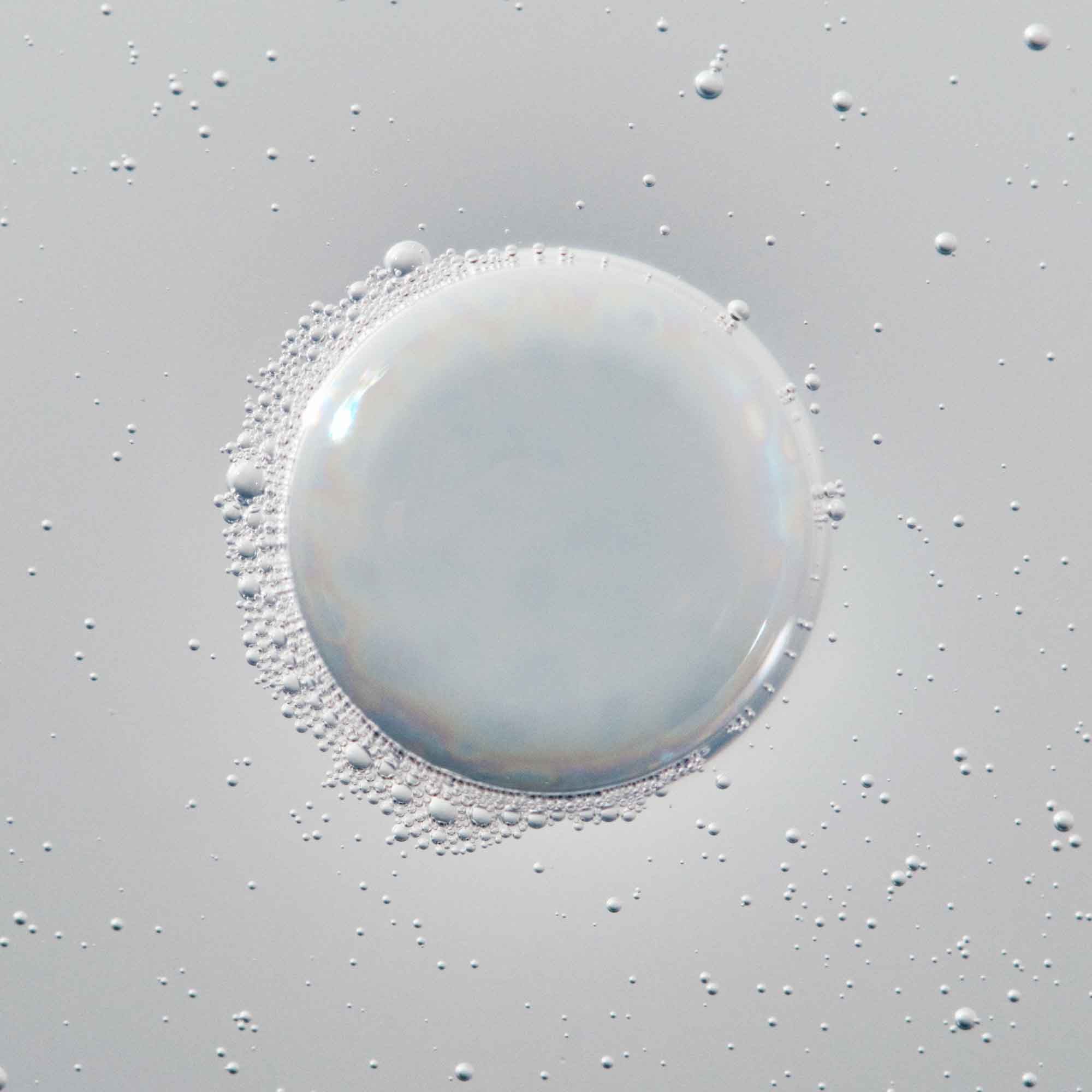 A large, translucent bubble surrounded by smaller bubbles on a smooth, light gray surface evokes the effect of Full Volume & Root-Lifting Spray, which delivers all-day fullness and weightless lift.