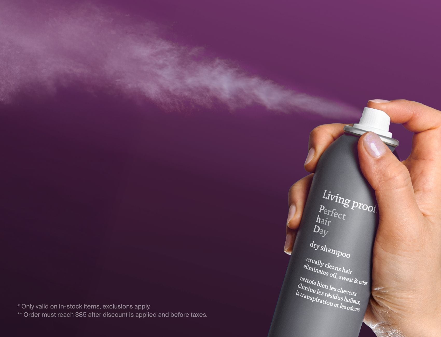 Living Proof dry shampoo can being sprayed against a purple background