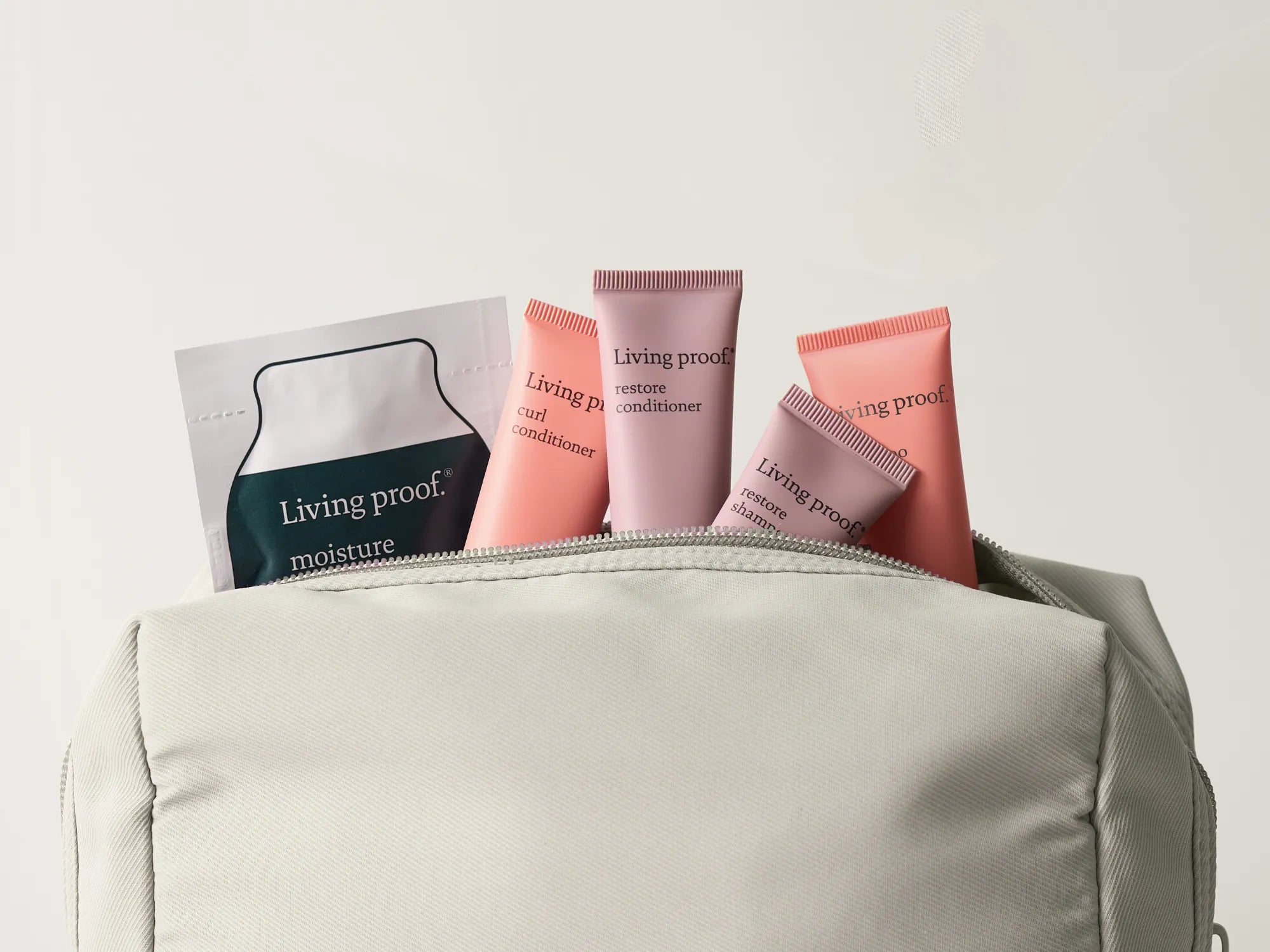 Living Proof haircare products in a beige bag on a light gray background