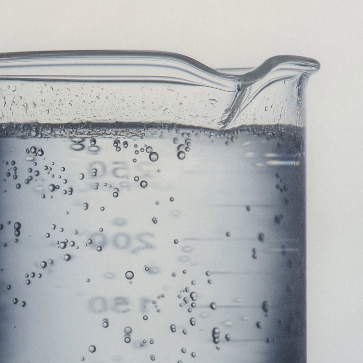 Close-up of a beaker with bubbling liquid on a light gray background