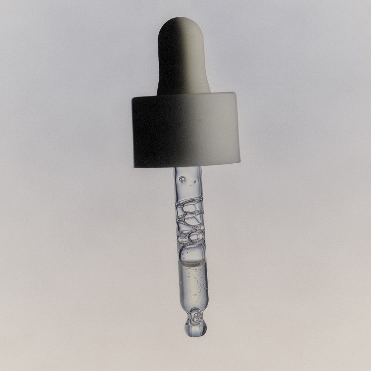 Glass dropper with black cap on a light gray background