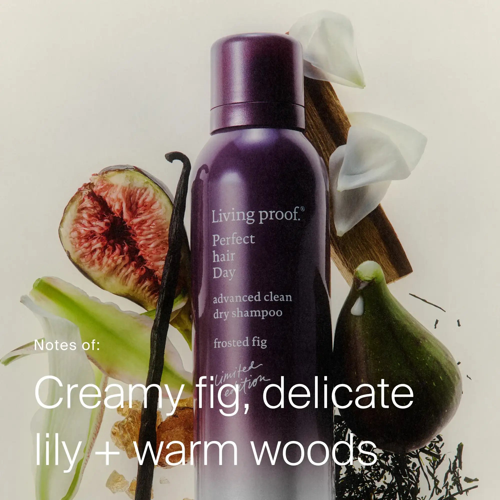 A limited-edition bottle of Perfect hair Day™ Frosted Fig Advanced Clean Dry Shampoo is surrounded by figs, white lilies, and wood. Text reads: Notes of: Creamy fig, delicate lily + warm woods.