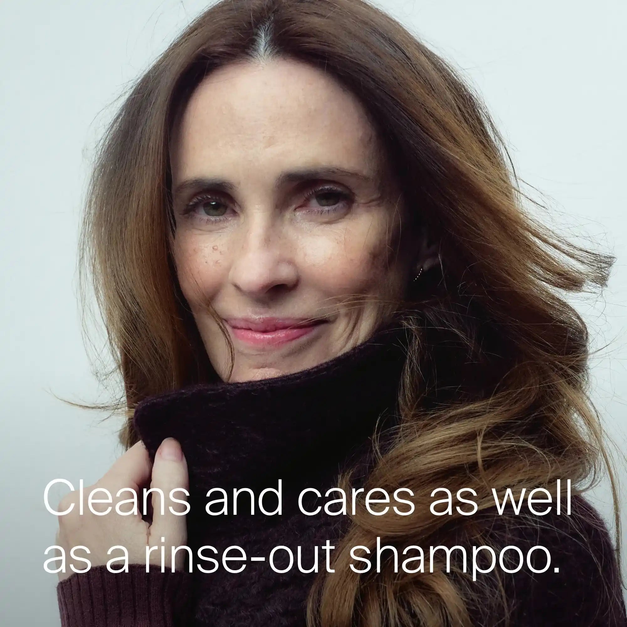 A woman with long brown hair smiles softly while wearing a dark sweater. Text reads, Cleans and cares as well as a rinse-out shampoo—now in Perfect hair Day™ Frosted Fig Advanced Clean Dry Shampoo, a limited-edition fig and coconut scent.