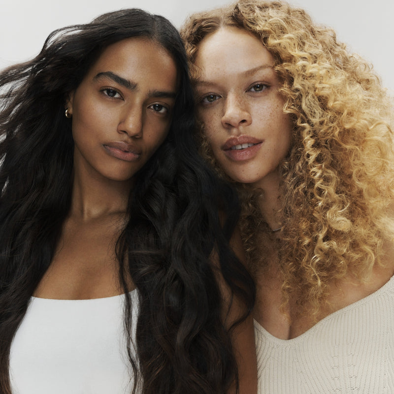 Woman with dark wavy hair and woman with light curly hair