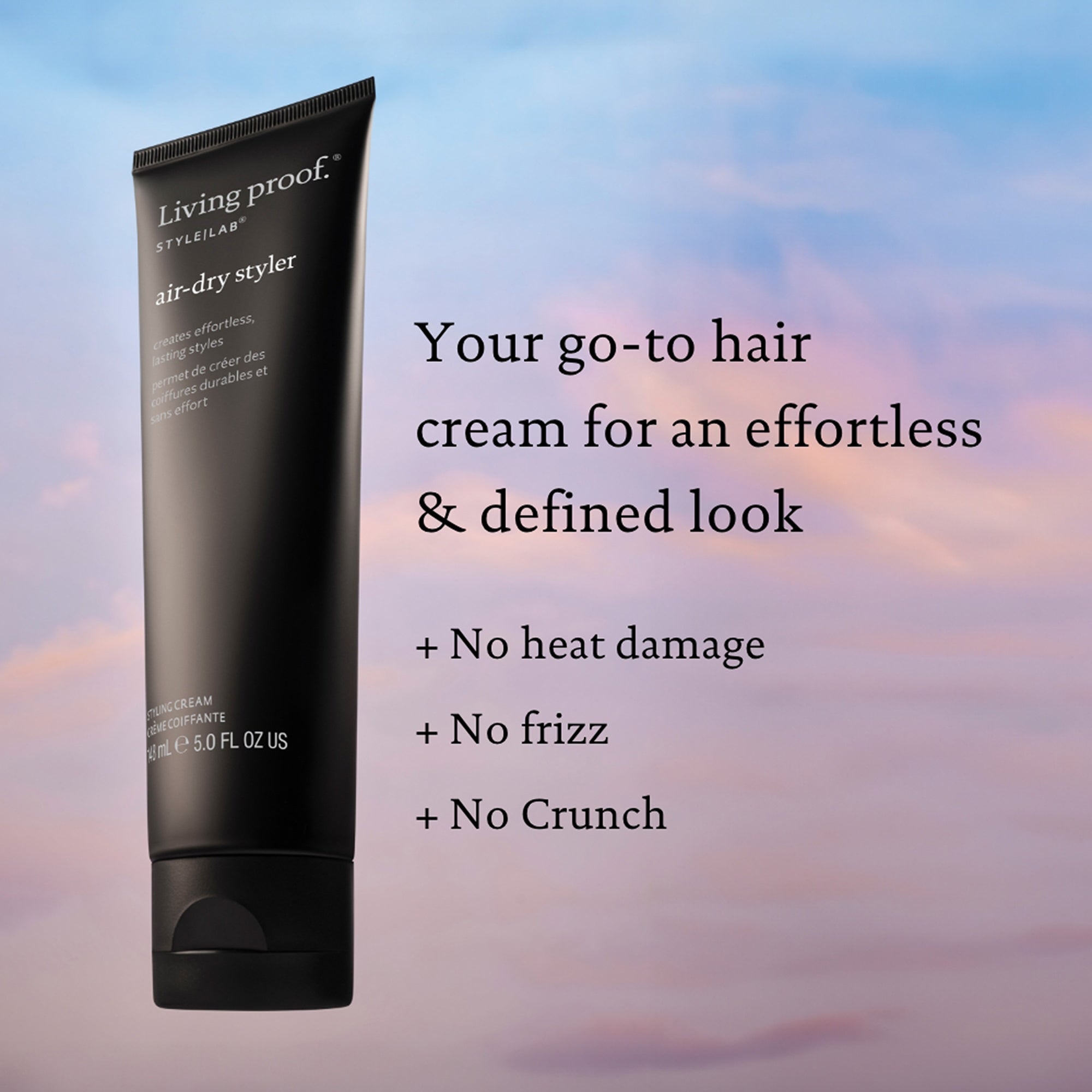 A tube of Style Lab® Air-Dry Styler hair cream appears against a pastel sky background. Text highlights its benefits: enhances natural texture, reduces frizz, delivers an effortless, defined look—no heat damage or crunch.
