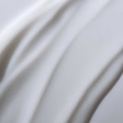 Close-up of smooth, creamy white liquid with gentle ridges and soft texture, evoking the soothing effect of No Frizz Conditioner for smooth, frizz-free hair in an abstract, calming scene.