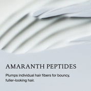 Close-up of Full Thickening Blow-Dry Cream, a creamy white formula with AMARANTH PEPTIDES. Plumps hair strands for bouncy, fuller-looking hair and adds heat protection. Soft pastel background.