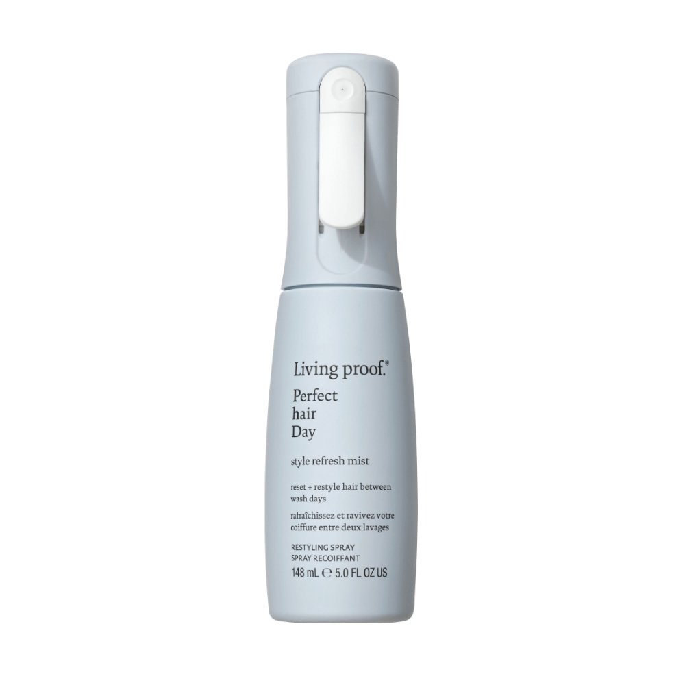 A light gray spray bottle labeled Perfect hair Day™ Style Refresh Mist stands upright on a white background, featuring a button nozzle and offering thermal protection plus hair reshaping benefits.