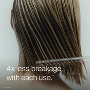 A person with wet, shoulder-length blonde hair uses a wide-tooth comb after applying Leave-In Conditioning Spray. Text reads: 4x less breakage and lasting detangling with each use.*.