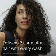A woman with long, thick, curly hair looks to the side, smiling slightly. Text on the image reads, Delivers 3x smoother hair with every wash thanks to Sili-CLONE HairTech. Fine print notes a consumer study on No Frizz Conditioner.