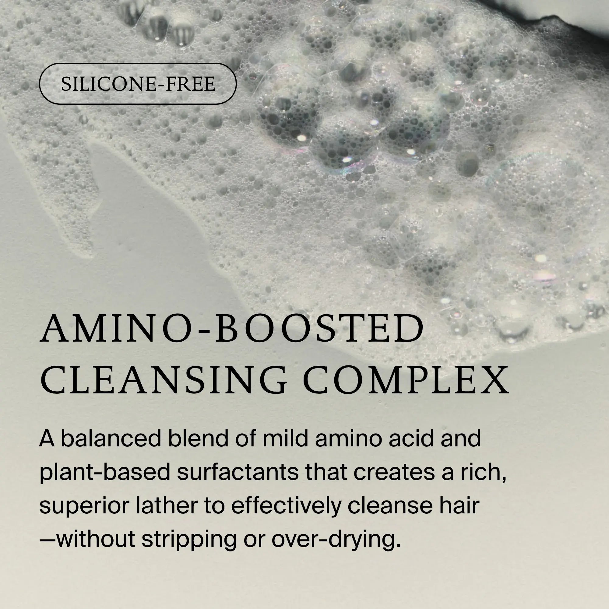 A close-up of foamy lather on a light surface with text: SILICONE-FREE. AMINO-BOOSTED CLEANSING COMPLEX. No Frizz Shampoo blends amino acids and plant-based surfactants for rich lather, smoothness, and frizz control—without over-drying.