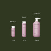 Three pink Restore Shampoo bottles by Living Proof in Travel (2 oz), Full (8 oz), and Jumbo (24 oz) sizes are displayed left to right on a dark green background, formulated with Sili-CLONE HairTech to improve hair texture.