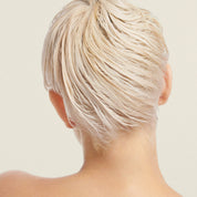 A person with short, platinum blonde, wet hair—shiny and soft from using the Restore Repair Mask—is shown from behind against a neutral background, with their neck and upper shoulders visible.