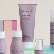 The Restore Repair Mask by Living Proof, in signature purple and white packaging, is set against a beige background and offers deep hydration and softness for your hair.