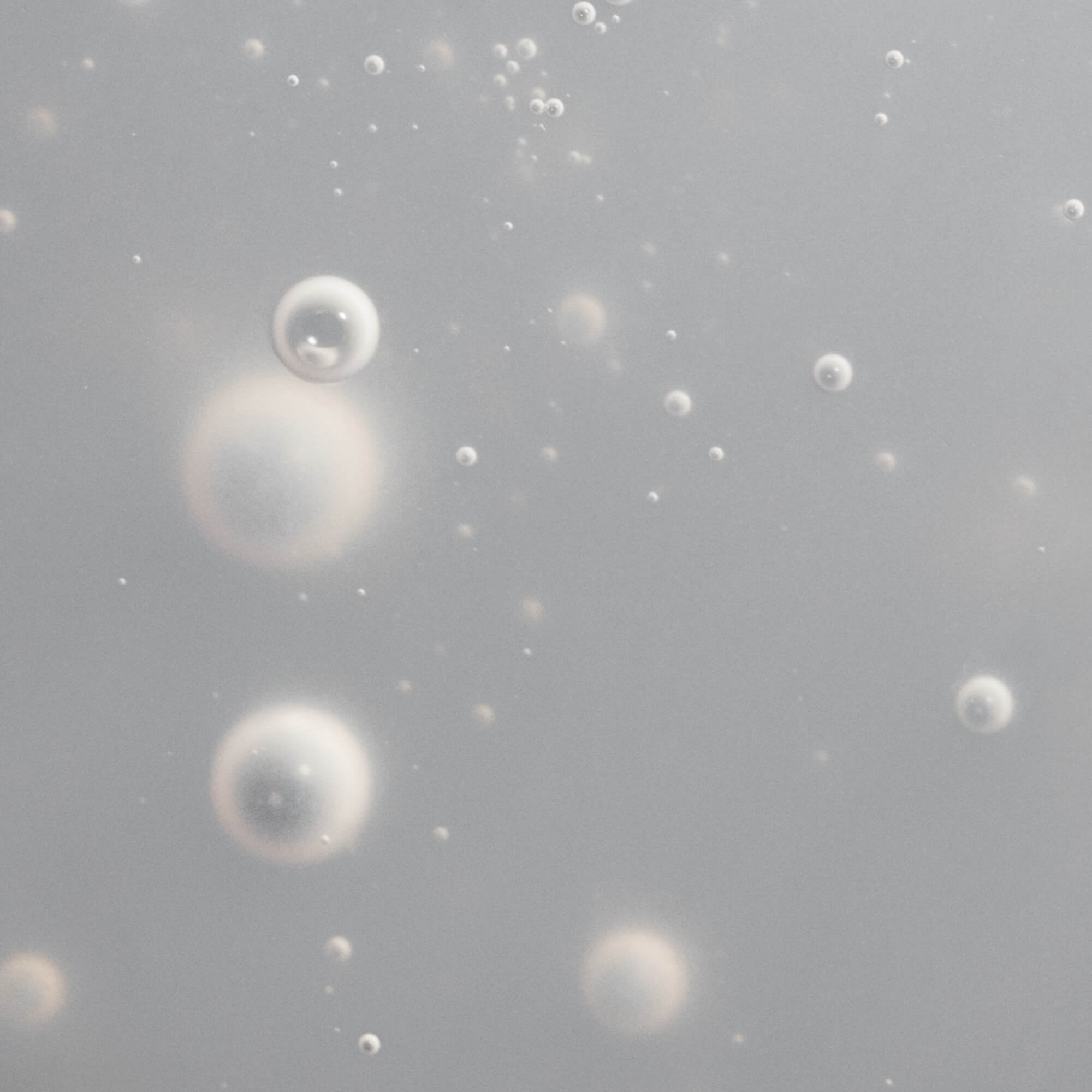 Translucent bubbles in a soft, light gray background evoke instant hydration and depth, reflecting the soothing, moisturizing benefits of Scalp Care Dry Scalp Treatment in this abstract and ethereal image.
