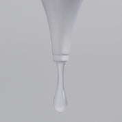 A close-up of a white Scalp Care Dry Scalp Treatment squeeze tube with a single drop of instant hydration about to fall from its tip against a plain, light gray background.