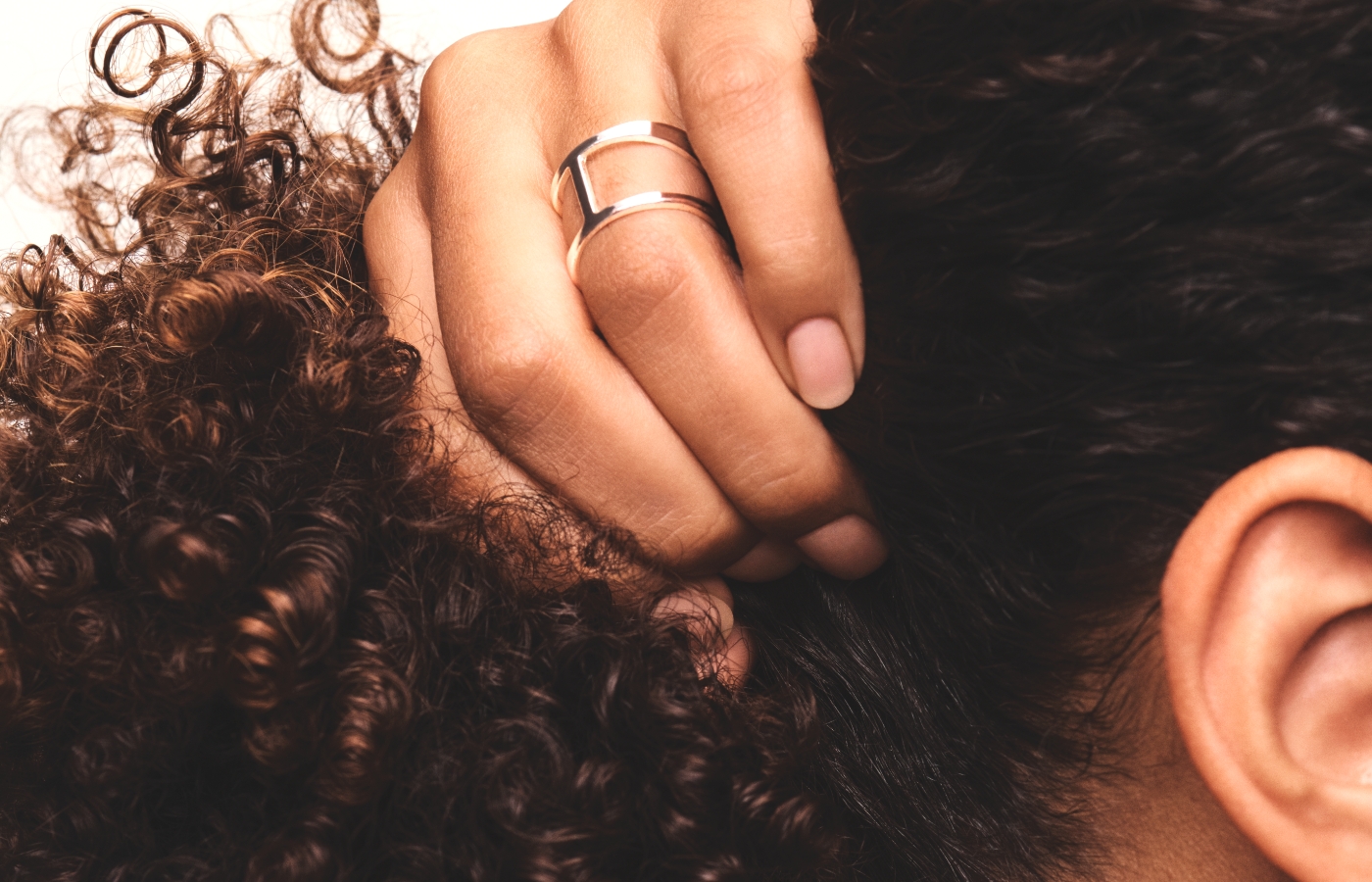 Hand brushing through dark brown hair.