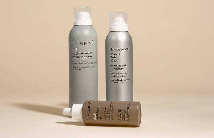 Three hair products against a beige surface.