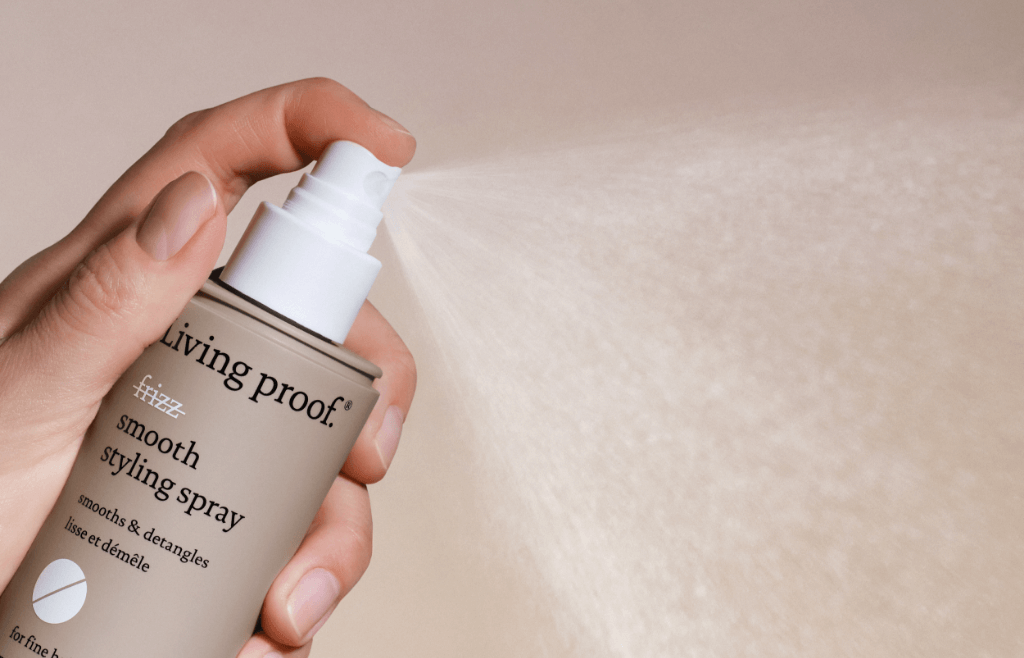 A bottle of Living Proof Smooth Styling Spray being sprayed