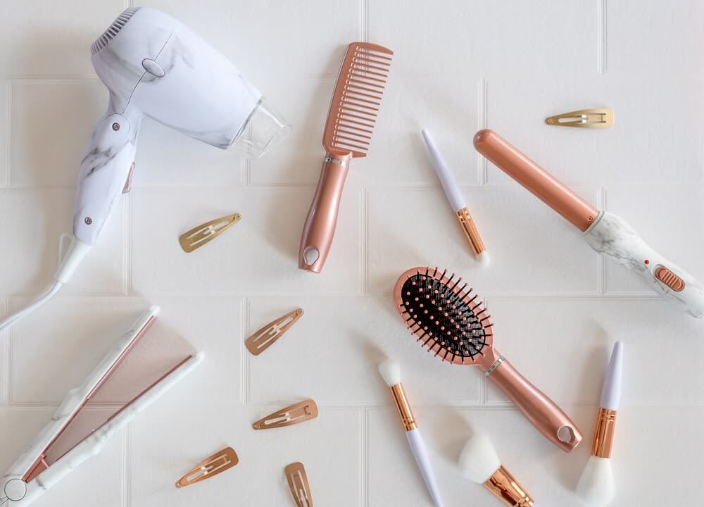 rose gold hair styling and make up products laid across a tiled background