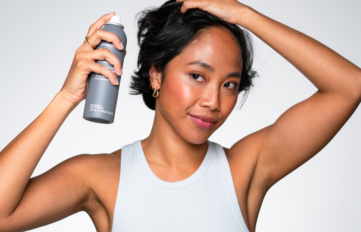 Woman spraying hair with Living Proof product.