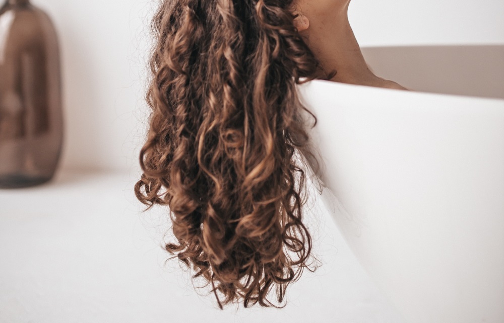 Woman with curly hair in a tub.