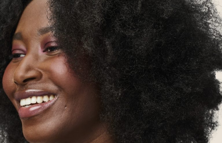A woman with black, curly hair smiling.